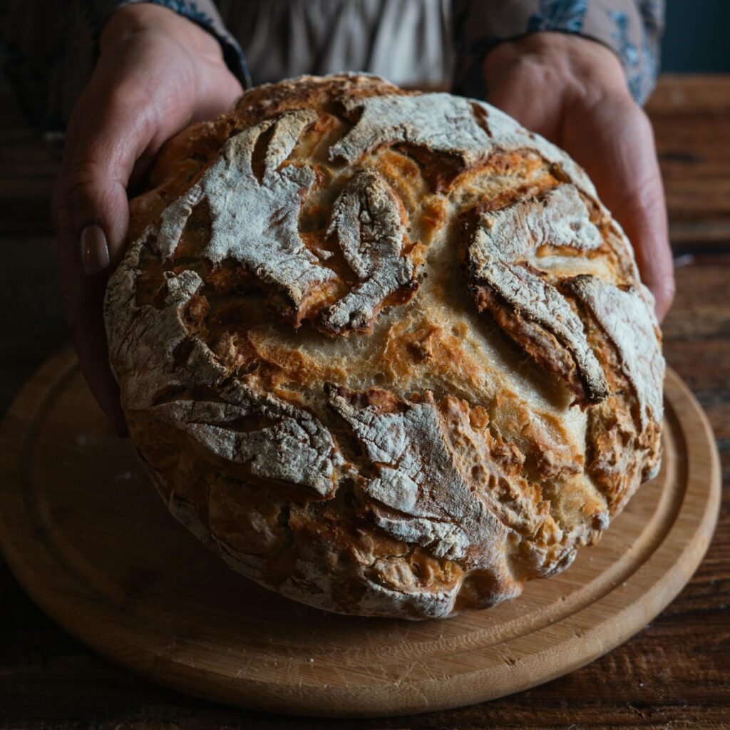 A close-up of rustic, freshly baked bread placed on a wooden table, ideal for artisan food themes.