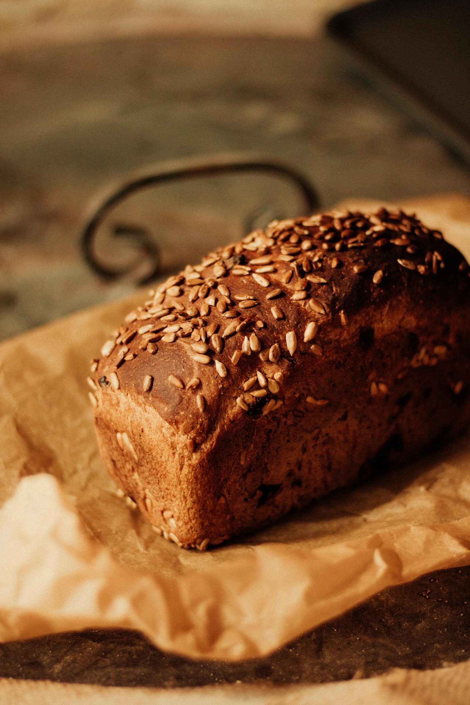 A delicious loaf of whole grain bread topped with seeds on parchment paper, exuding a warm, homemade feel.