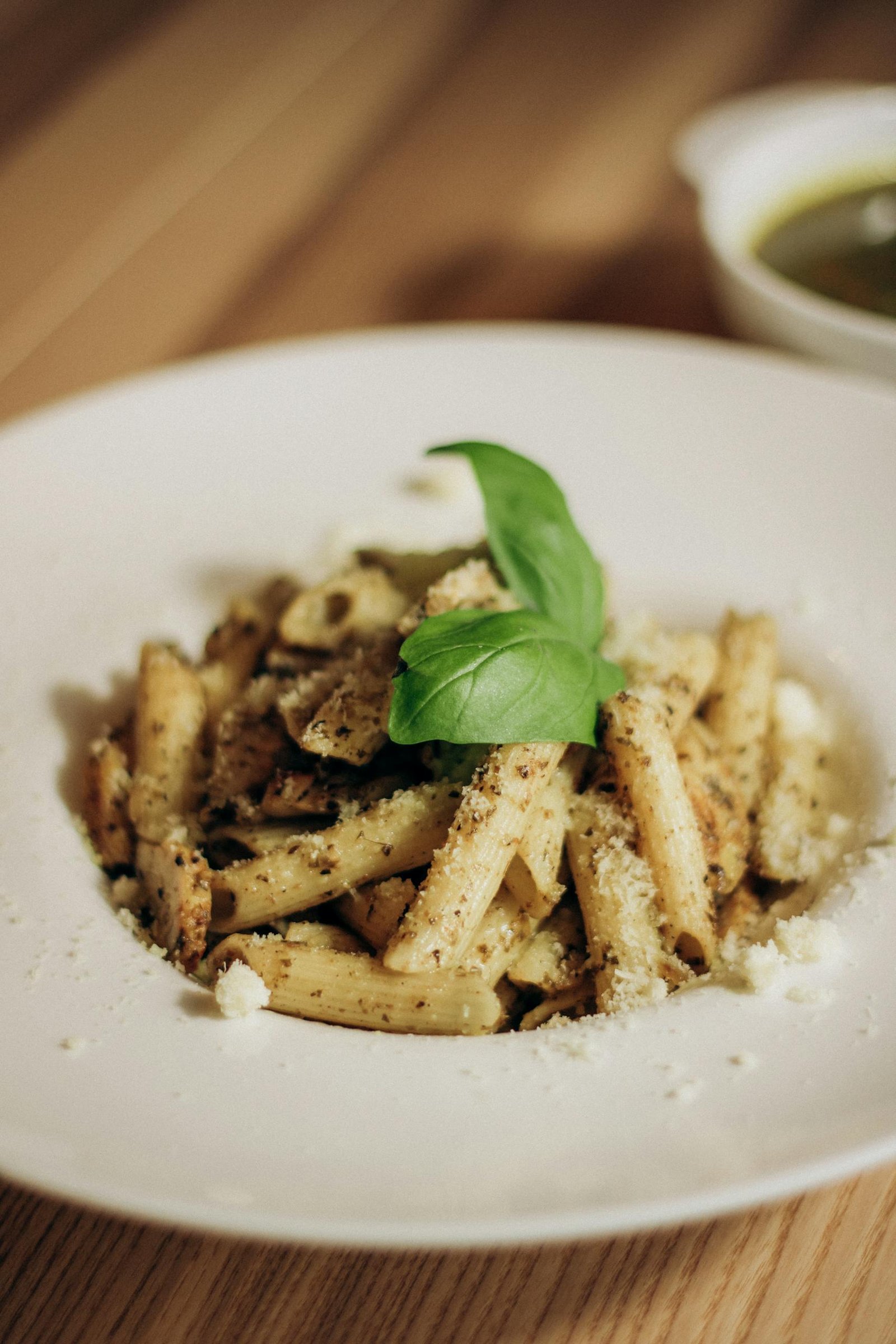 Close-up of creamy pasta topped with pesto and fresh basil, perfect for Italian cuisine lovers.