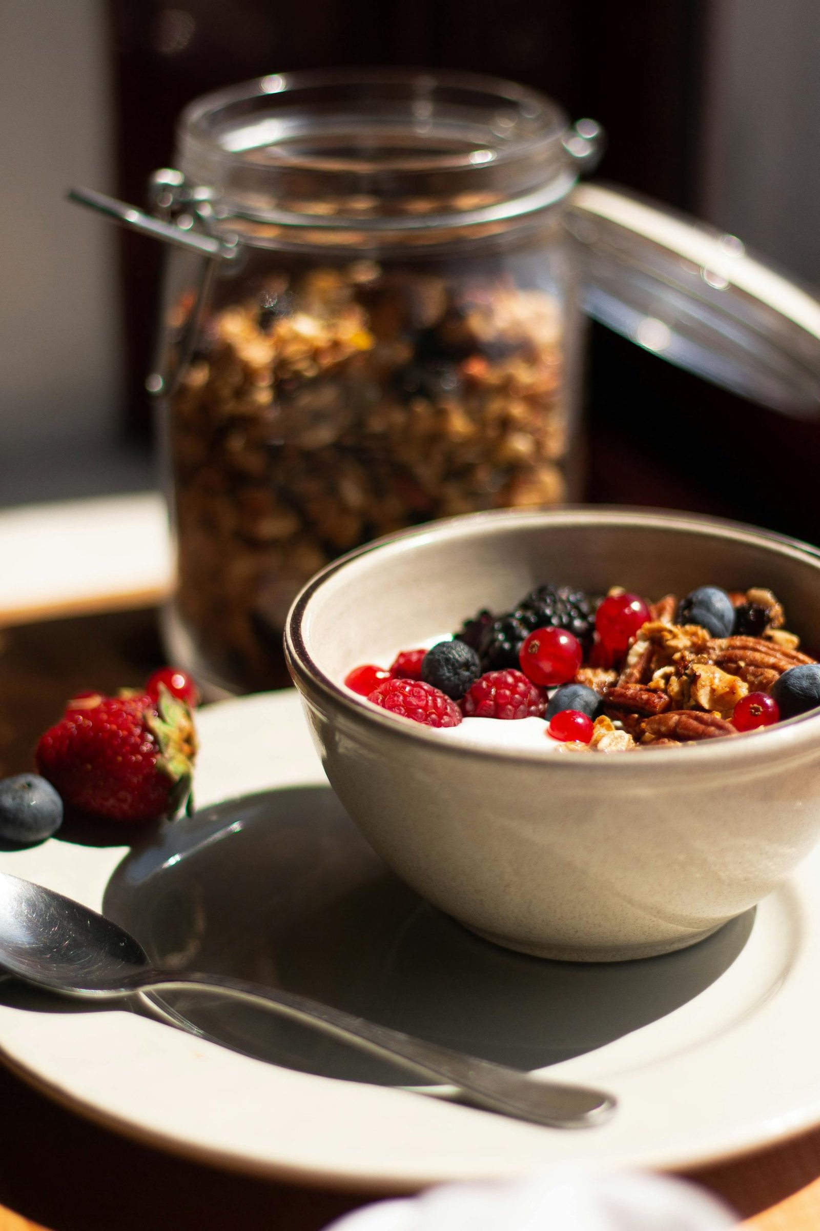 Nutritious breakfast bowl featuring yogurt, fresh berries, granola, and pecans in natural light.