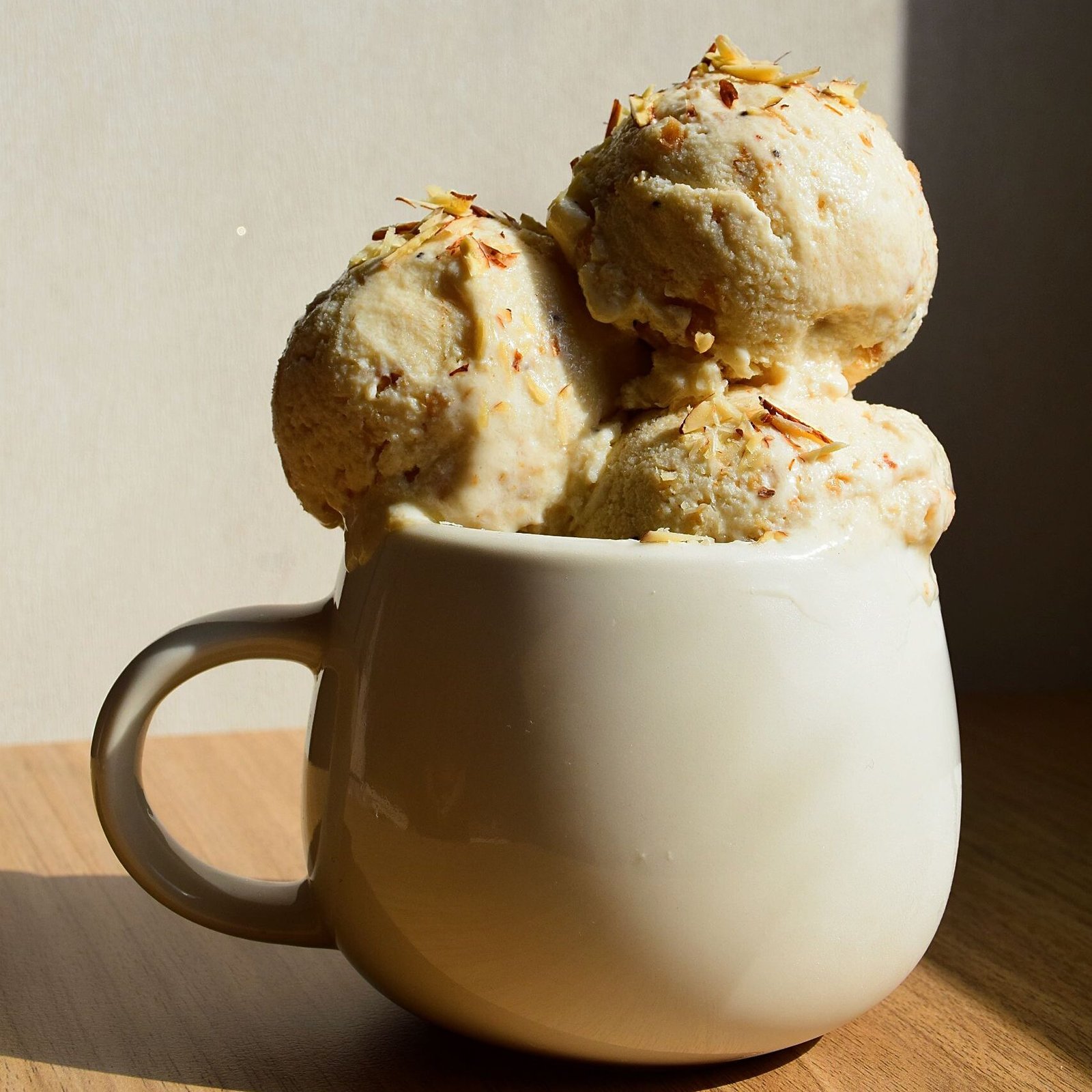 Delicious ice cream in a ceramic mug on a wooden table, perfect for dessert lovers.