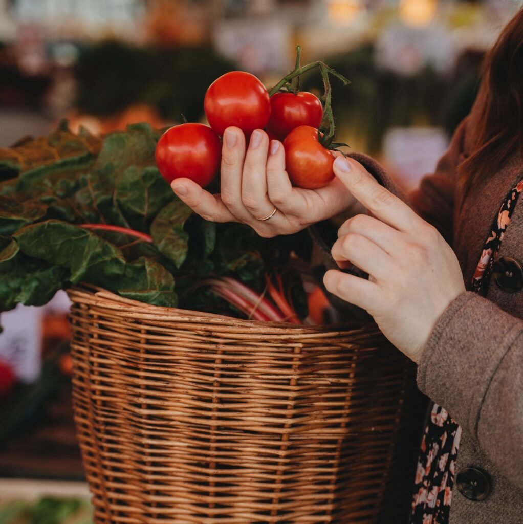 A woman selecting fresh tomatoes at an outdoor market in Erfurt, Germany.