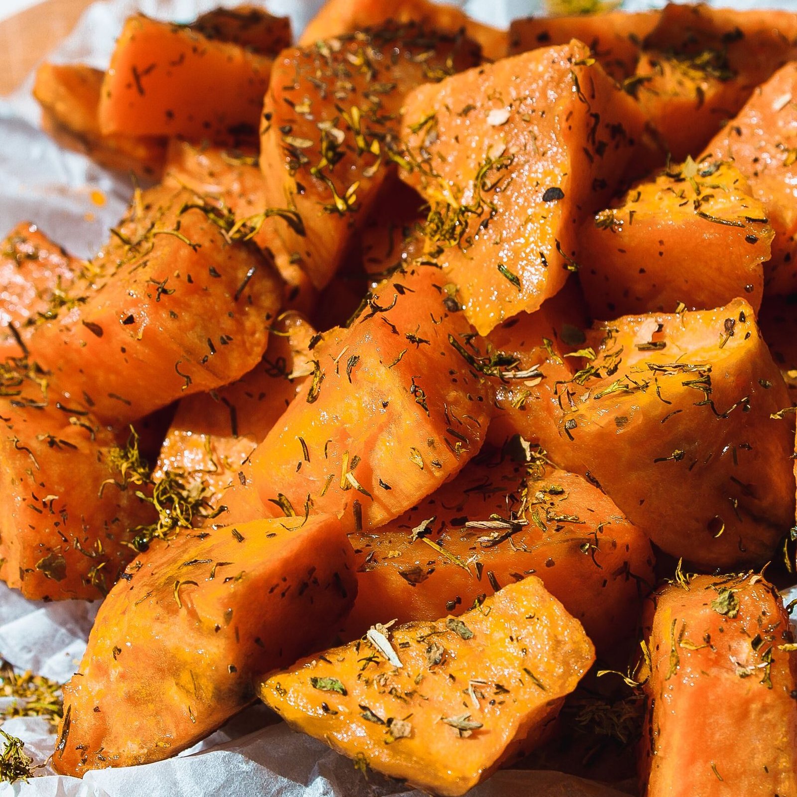 Close-up of delicious baked sweet potatoes seasoned with herbs, perfect for a healthy meal.